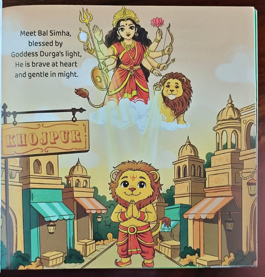 A children's book or printed card featuring an illustrated scene with a crowned goddess in red and gold standing on clouds above a lion, with a smaller lion child in front of a city street labeled Khajur. Text on the left reads, 'Meet Bal Simha, blessed by Goddess Durga's light, He is brave at heart and gentle in might.