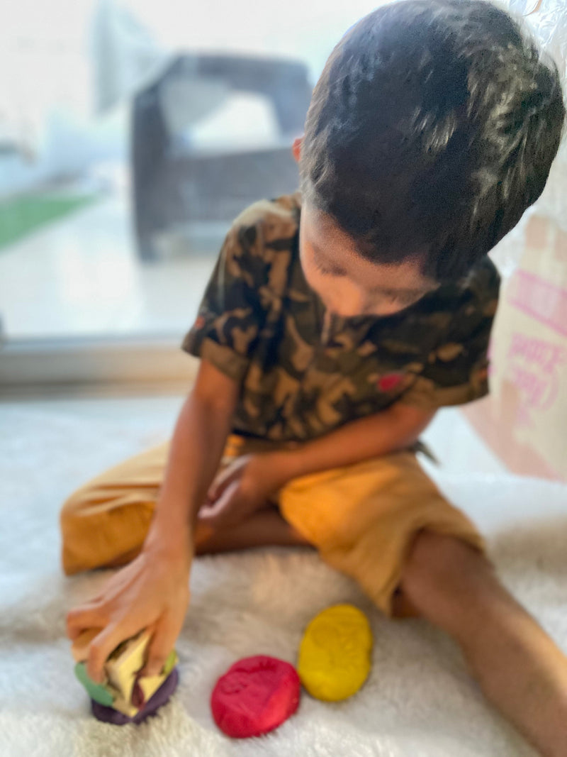 A small boy making impressions on clay dough using wooden dice
